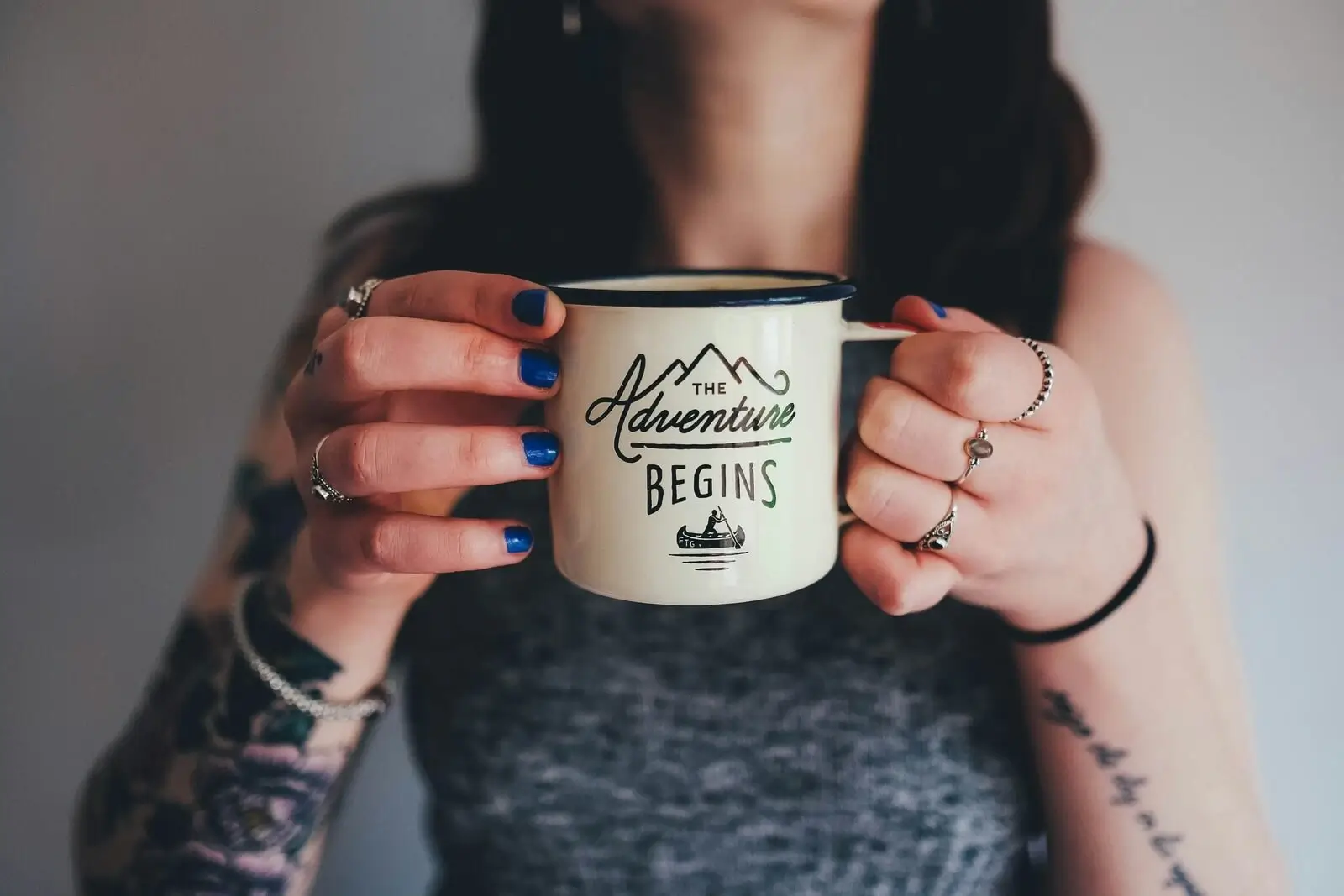 Peron holding a coffee cup that reads, "The Adventure Begins"